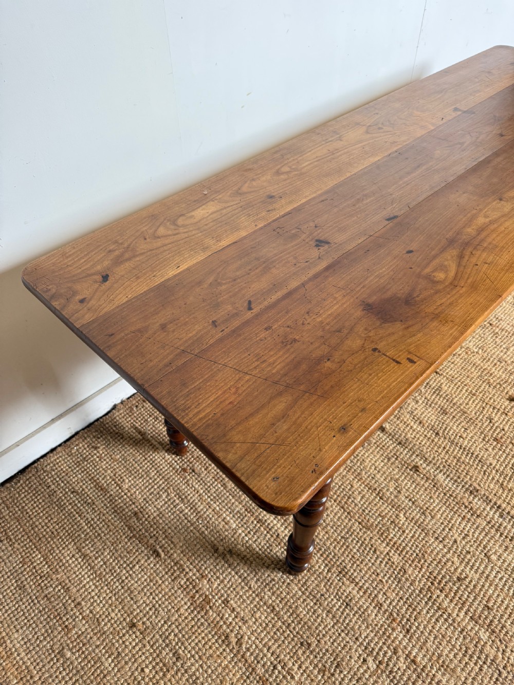 An antique rectangular cherrywood console table with a plank top, single central drawer with a turned knob, and four baluster turned legs. View VII