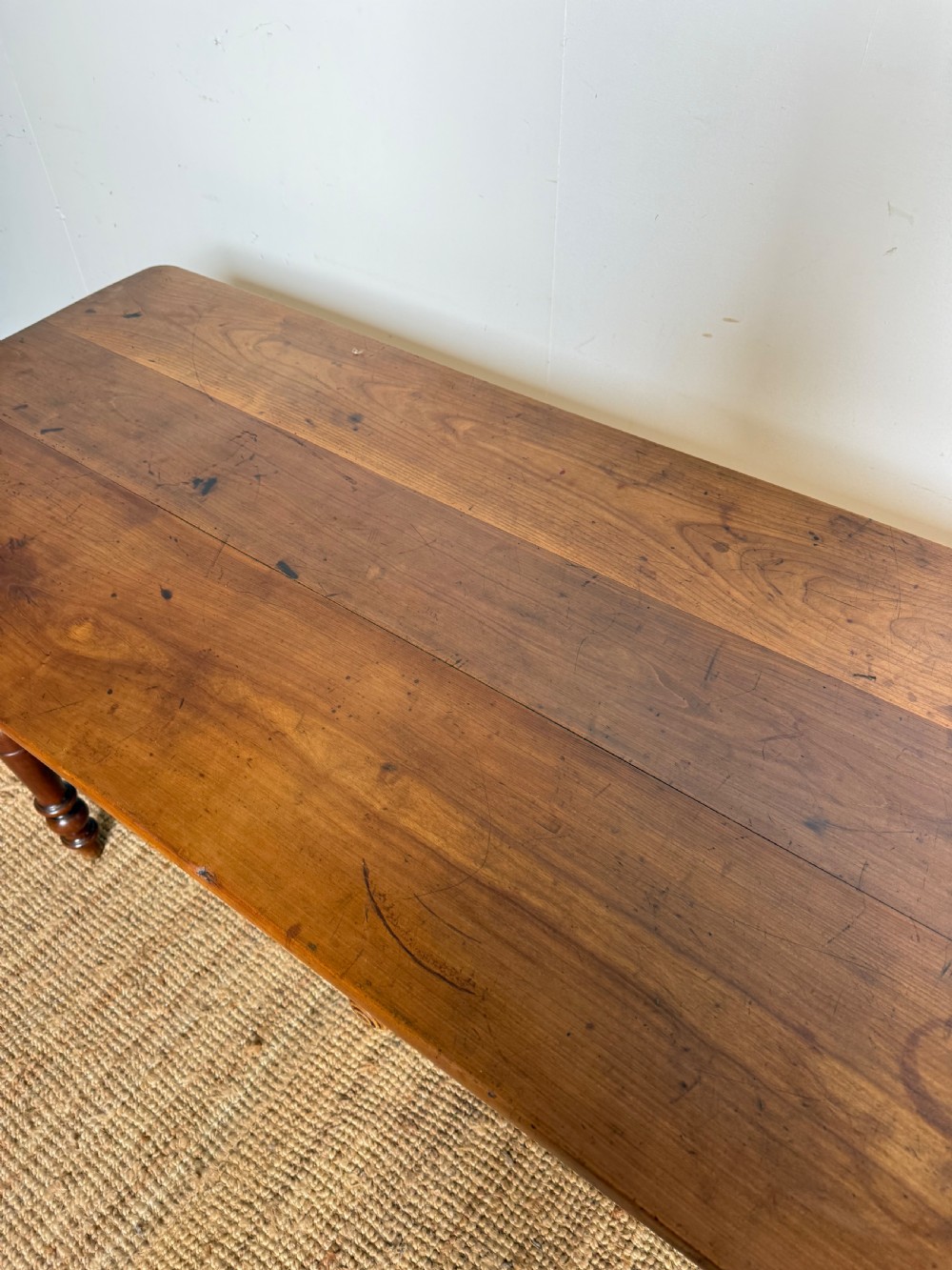 An antique rectangular cherrywood console table with a plank top, single central drawer with a turned knob, and four baluster turned legs. View VIII