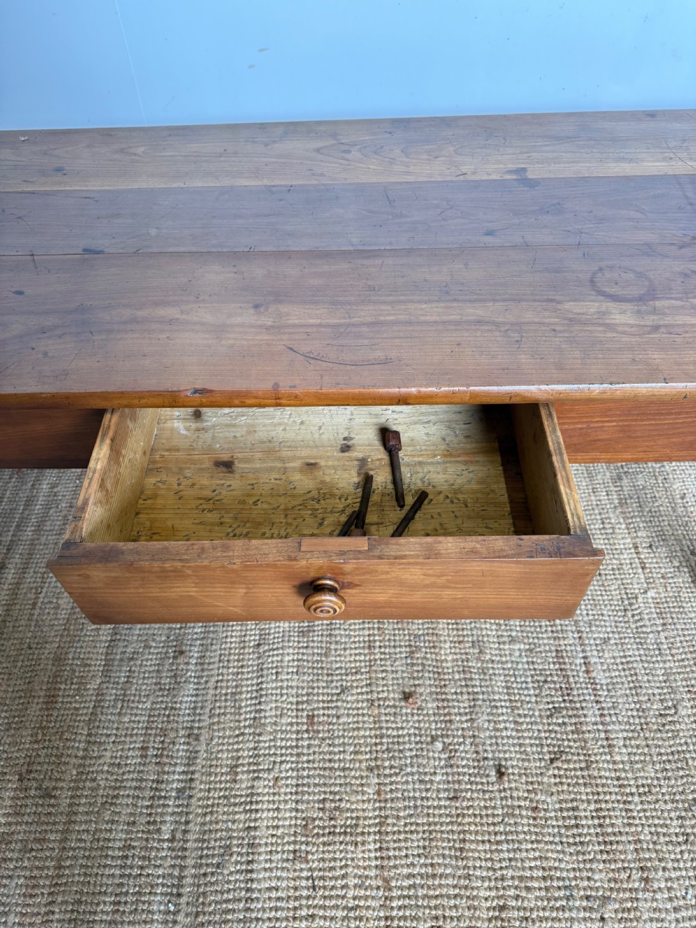 An antique rectangular cherrywood console table with a plank top, single central drawer with a turned knob, and four baluster turned legs. View X