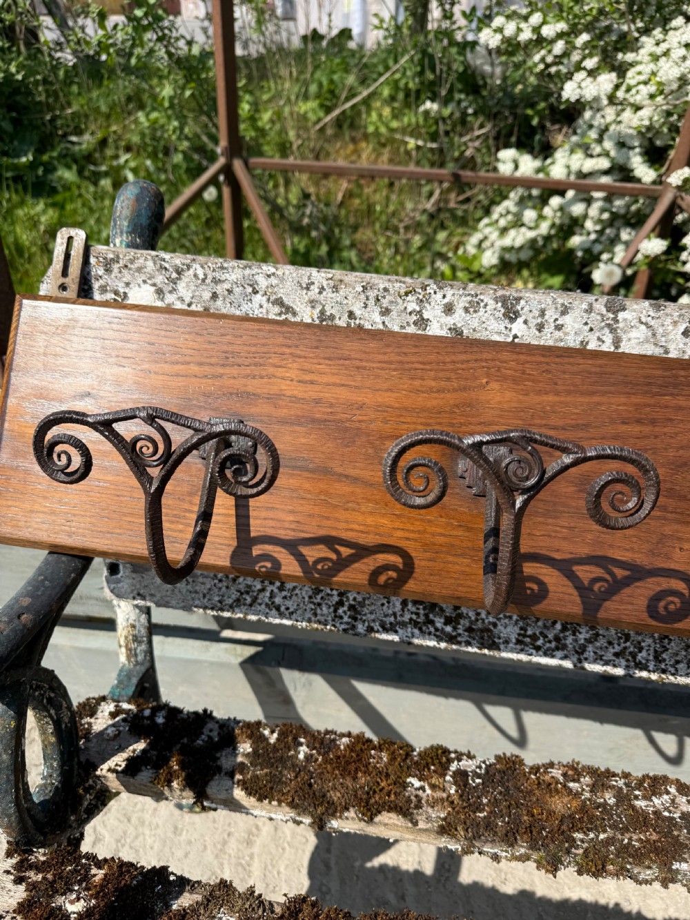 A wall-mounted dark oak coat rack featuring six scroll-shaped wrought iron hooks evenly spaced along a rectangular wooden backboard. View VI