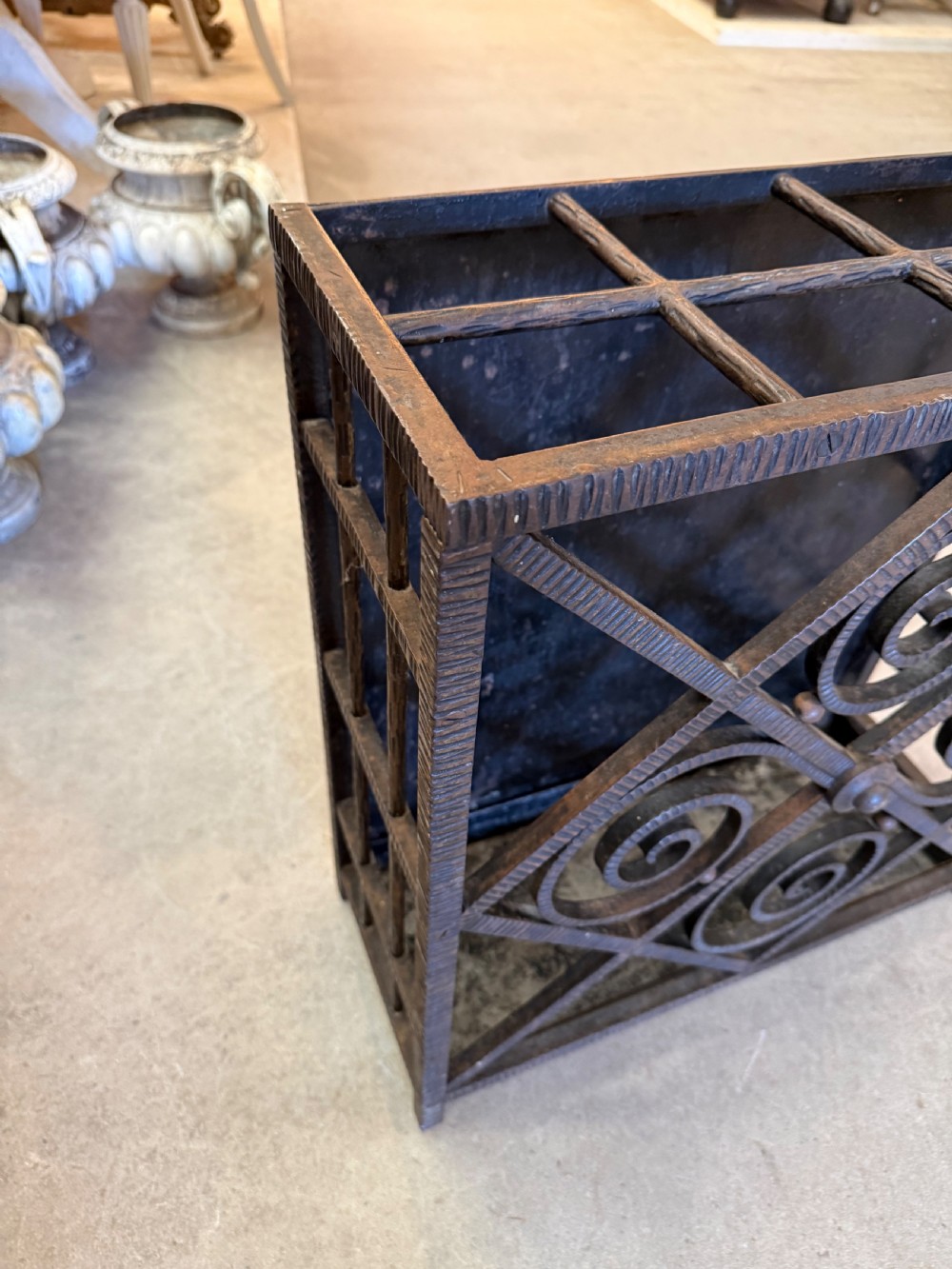 An Art Deco wrought iron umbrella stand featuring a dark hammered finish, central spiral motifs inside a diamond frame, and top section dividers. View III