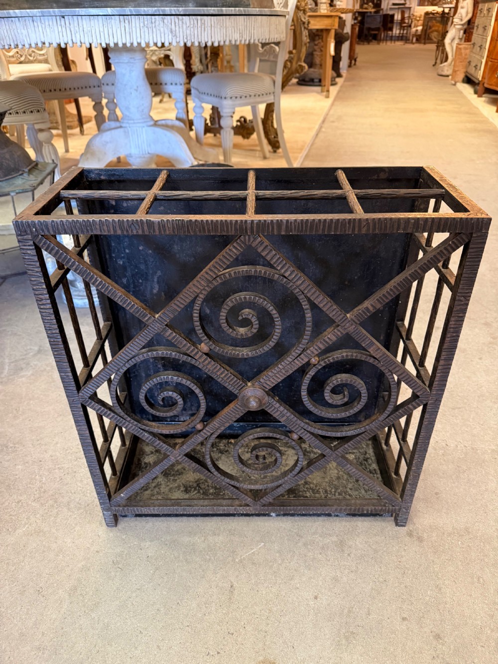 An Art Deco wrought iron umbrella stand featuring a dark hammered finish, central spiral motifs inside a diamond frame, and top section dividers. View IV