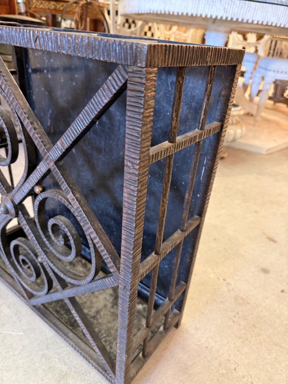 An Art Deco wrought iron umbrella stand featuring a dark hammered finish, central spiral motifs inside a diamond frame, and top section dividers. View VII