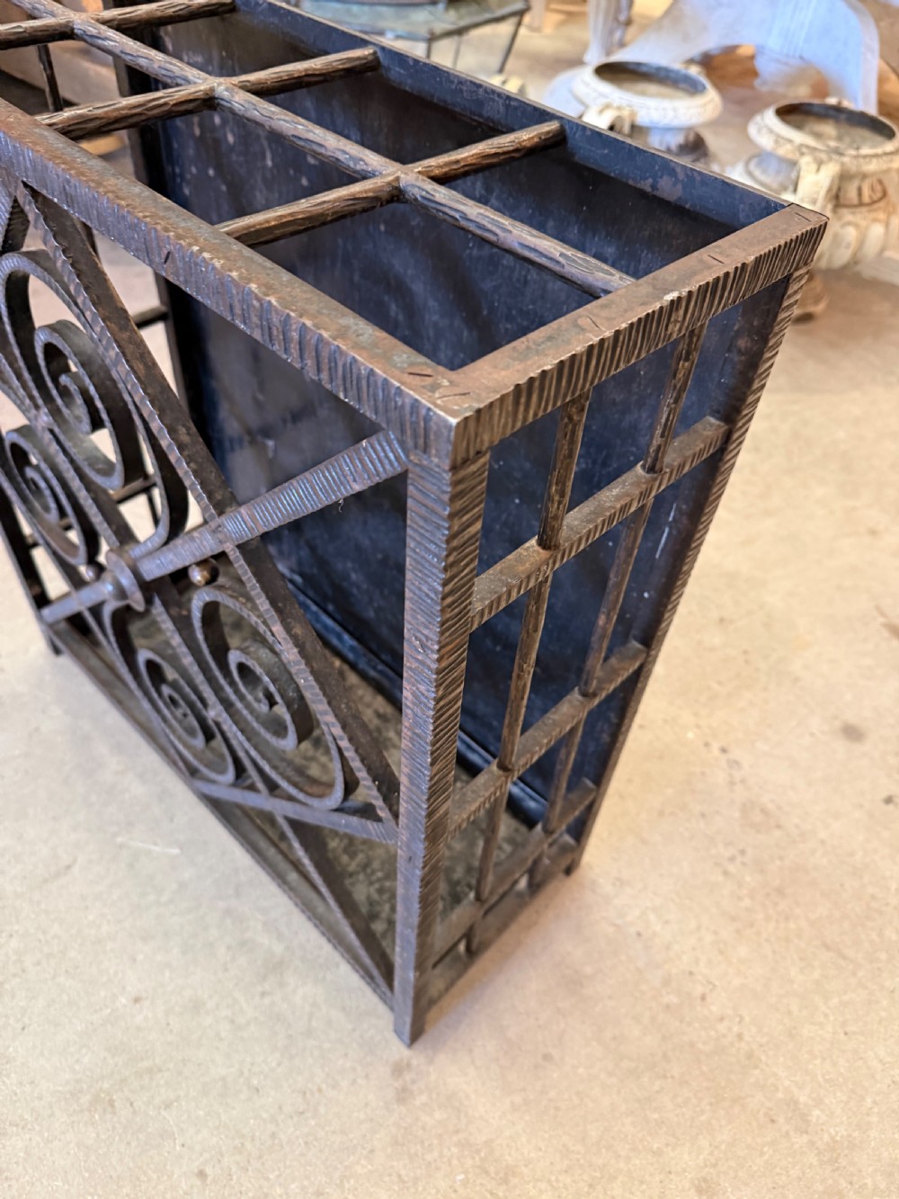 An Art Deco wrought iron umbrella stand featuring a dark hammered finish, central spiral motifs inside a diamond frame, and top section dividers. View VIII