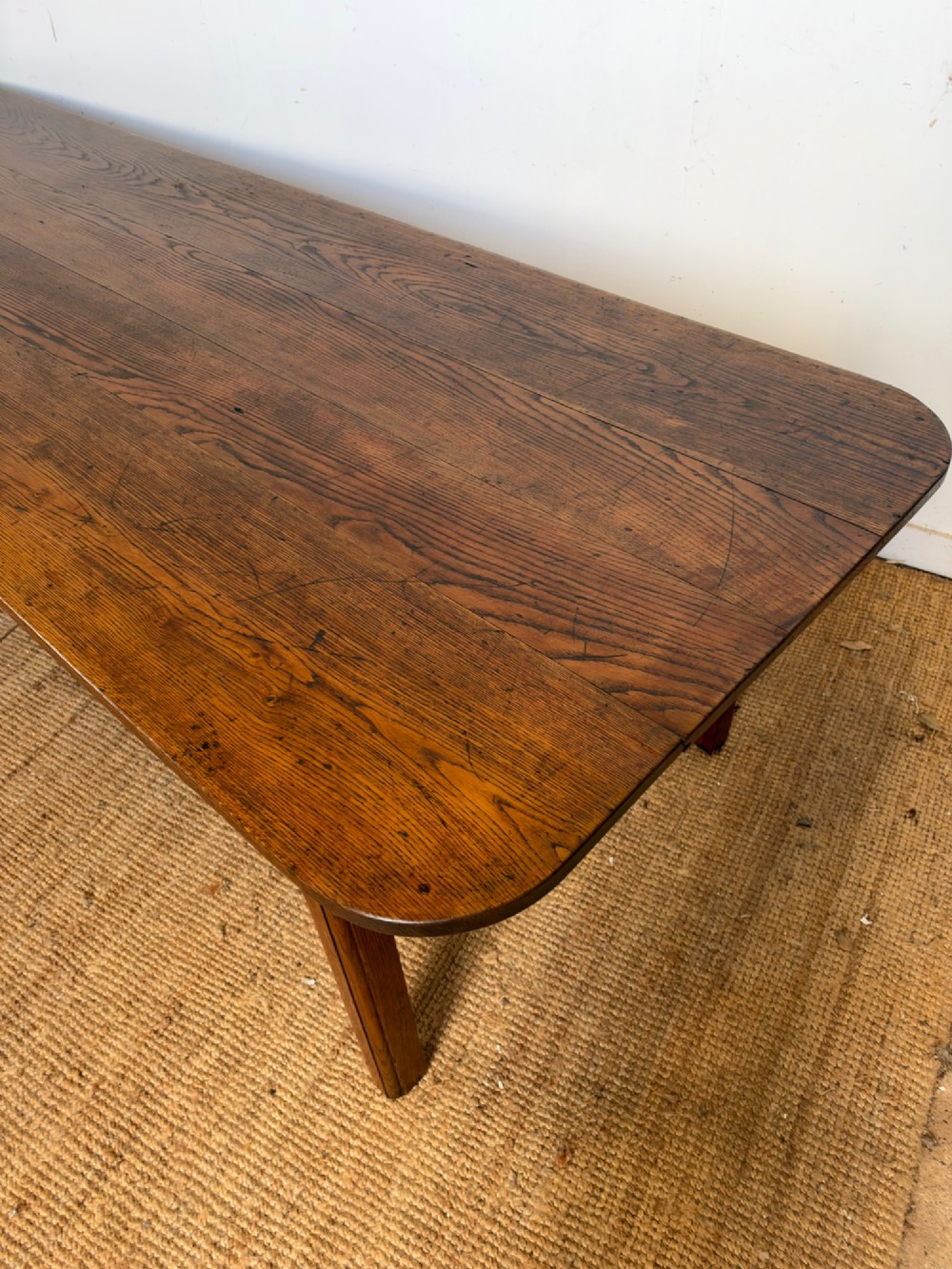 A large late nineteenth-century solid oak farmhouse dining table featuring a plank top with rounded corners and four straight legs. View IV