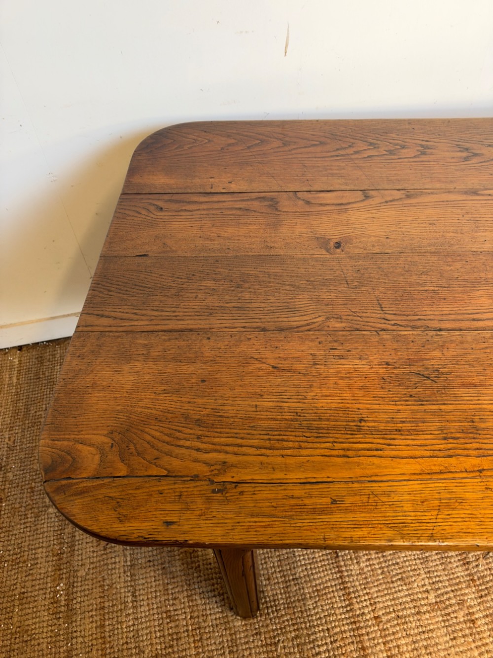 A large late nineteenth-century solid oak farmhouse dining table featuring a plank top with rounded corners and four straight legs. View X