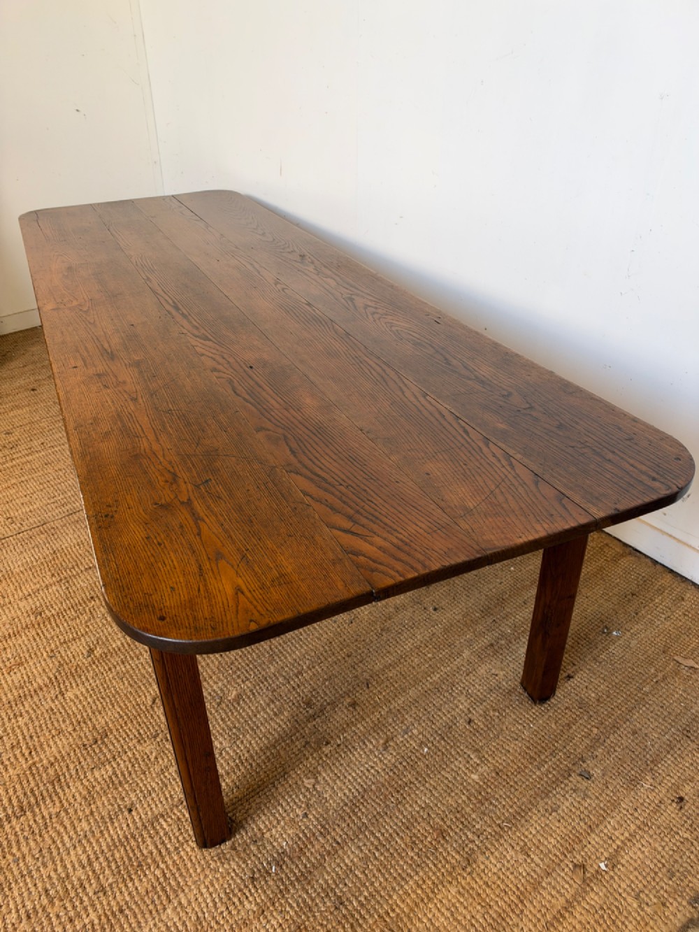 A large late nineteenth-century solid oak farmhouse dining table featuring a plank top with rounded corners and four straight legs. View XIII