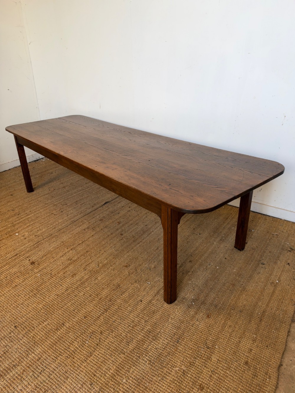 A large late nineteenth-century solid oak farmhouse dining table featuring a plank top with rounded corners and four straight legs. View XV