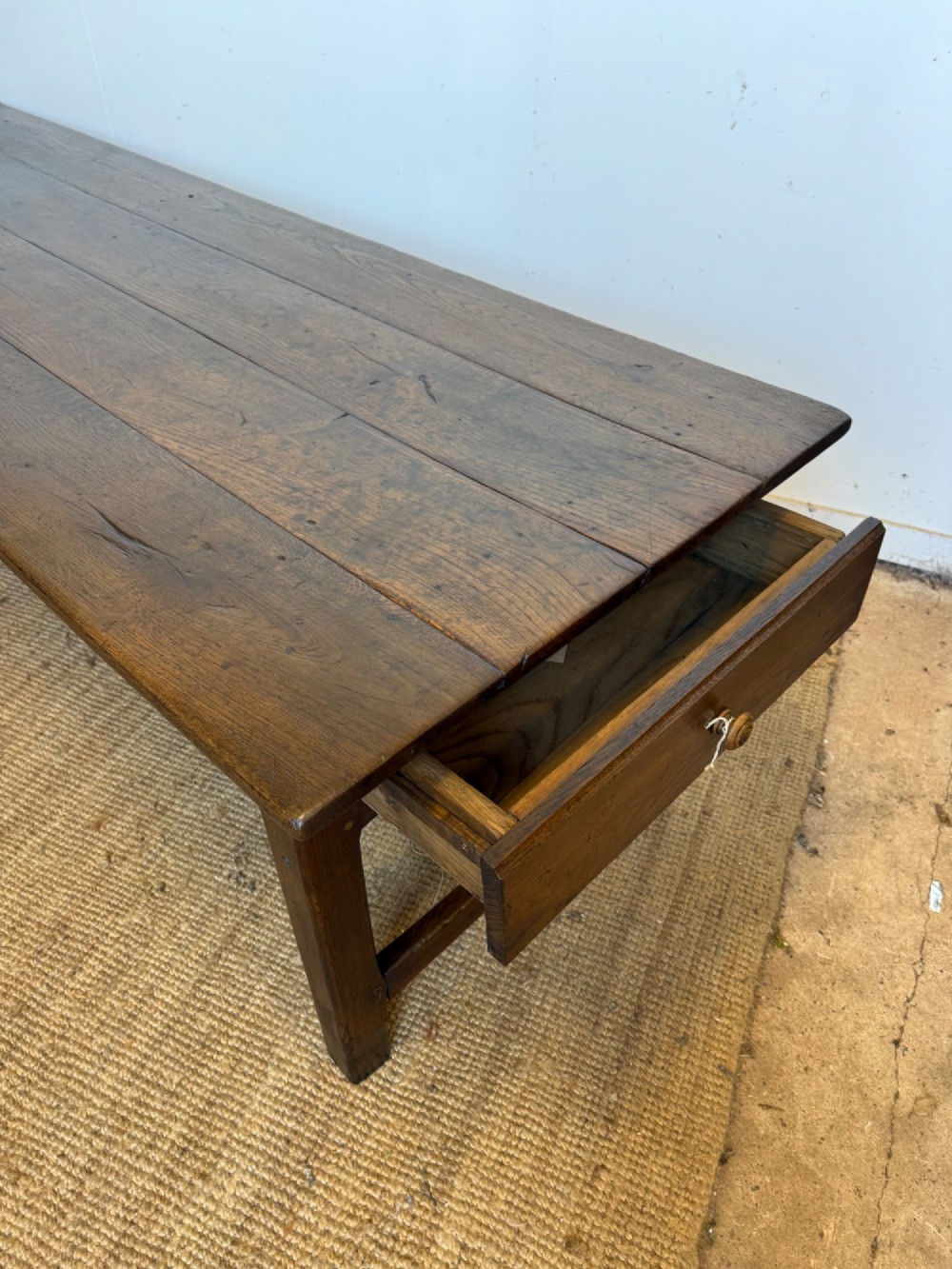 A long dark oak French farmhouse dining table with a plank top and an H-stretcher base structure. View III