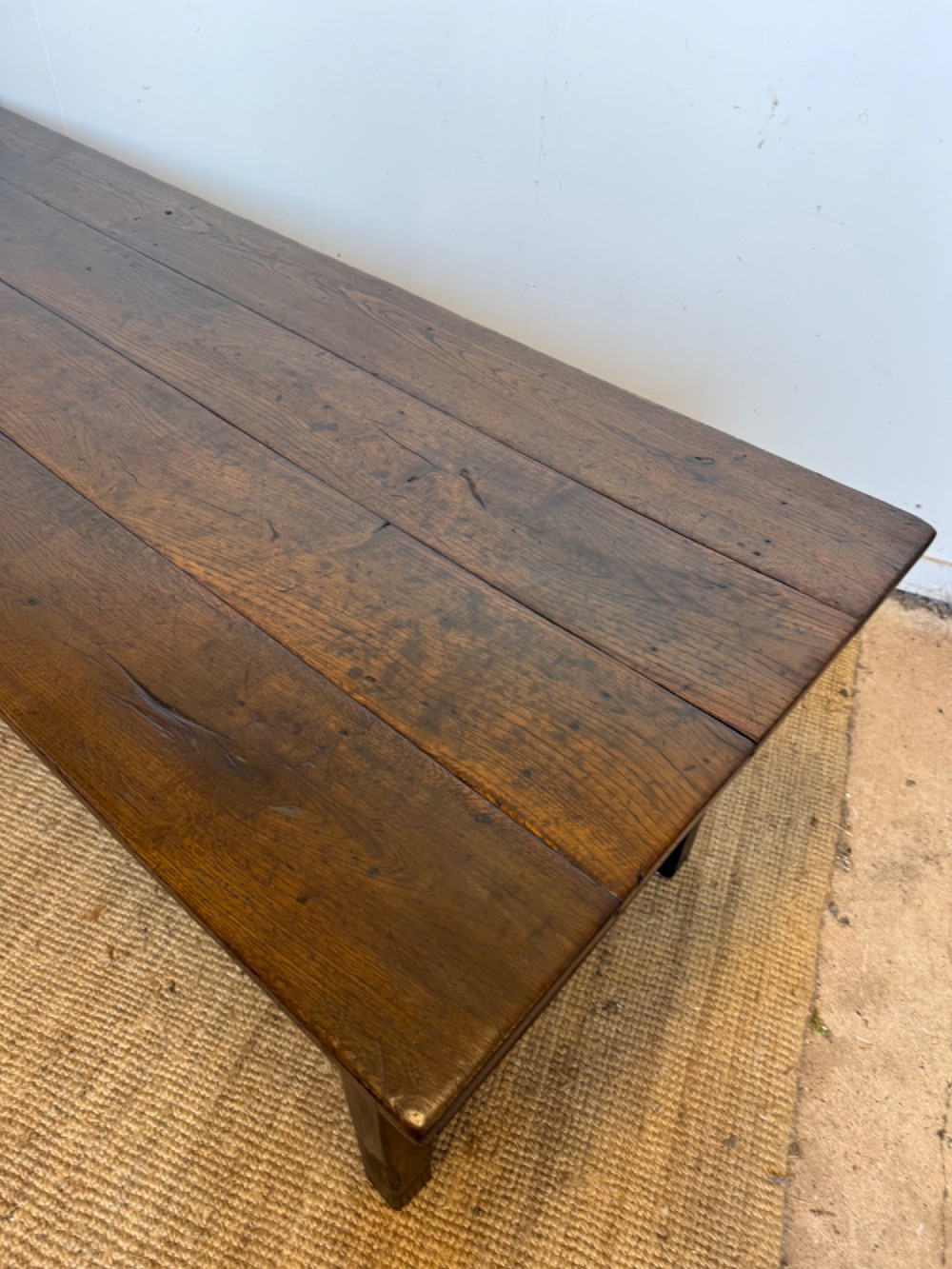 A long dark oak French farmhouse dining table with a plank top and an H-stretcher base structure. View IV