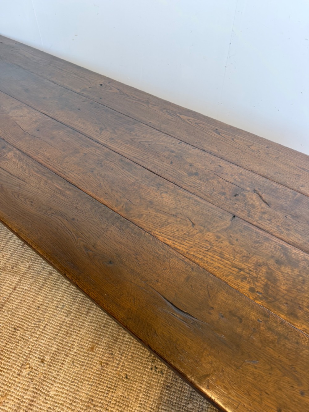 A long dark oak French farmhouse dining table with a plank top and an H-stretcher base structure. View V
