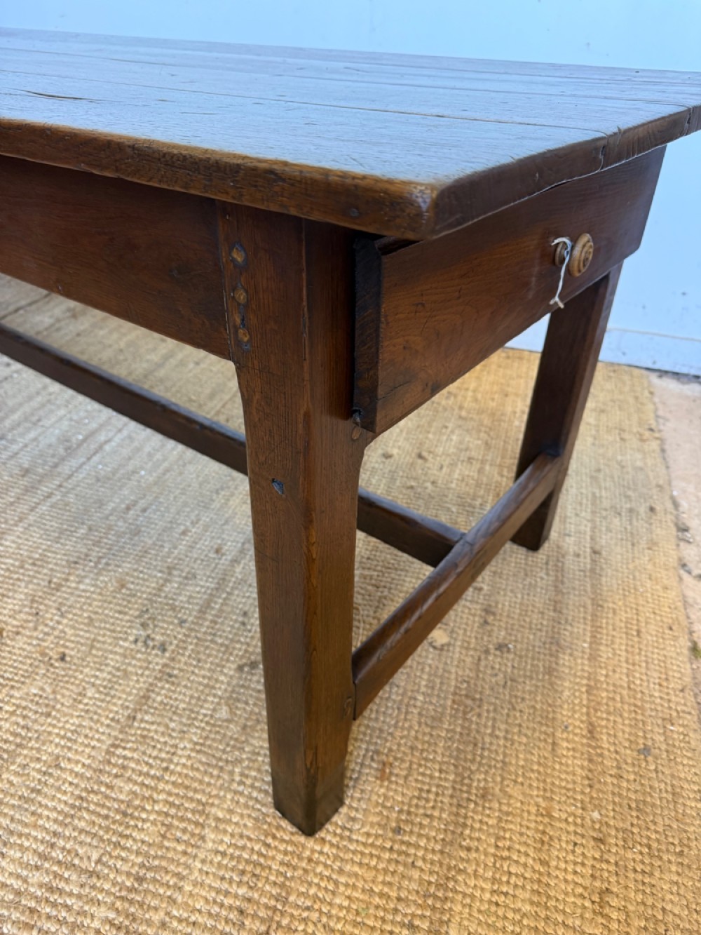 A long dark oak French farmhouse dining table with a plank top and an H-stretcher base structure. View XI