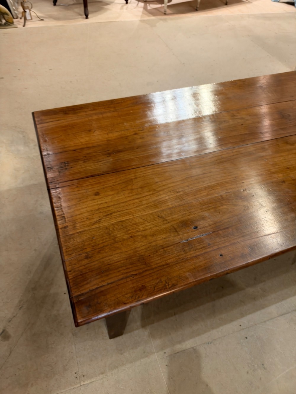 A large rectangular warm brown cherrywood coffee table featuring a plank top, tapered square legs, and a small drawer with a ring pull handle. View III