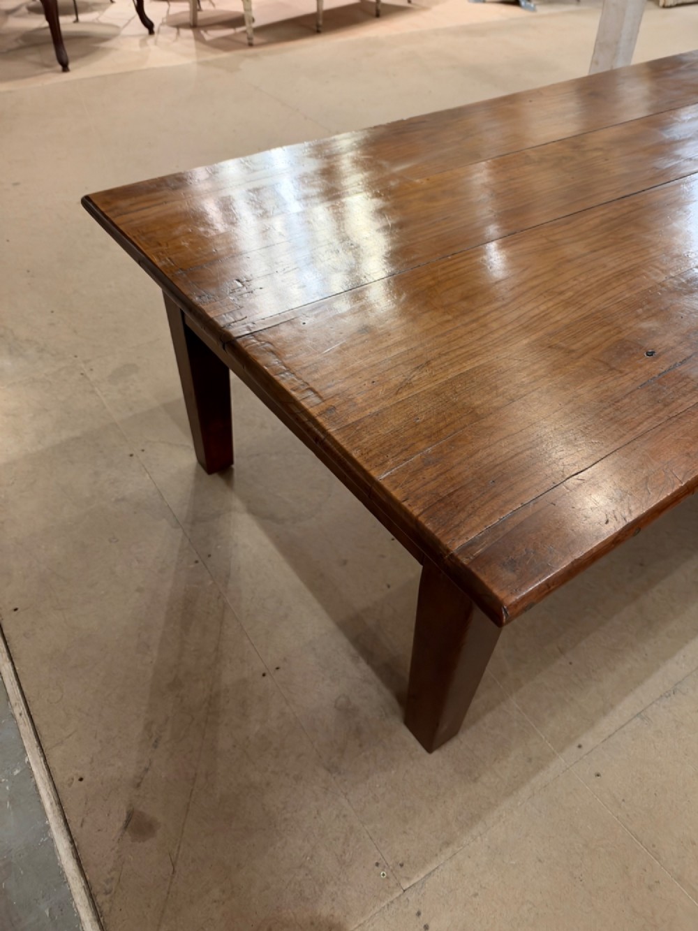 A large rectangular warm brown cherrywood coffee table featuring a plank top, tapered square legs, and a small drawer with a ring pull handle. View VII