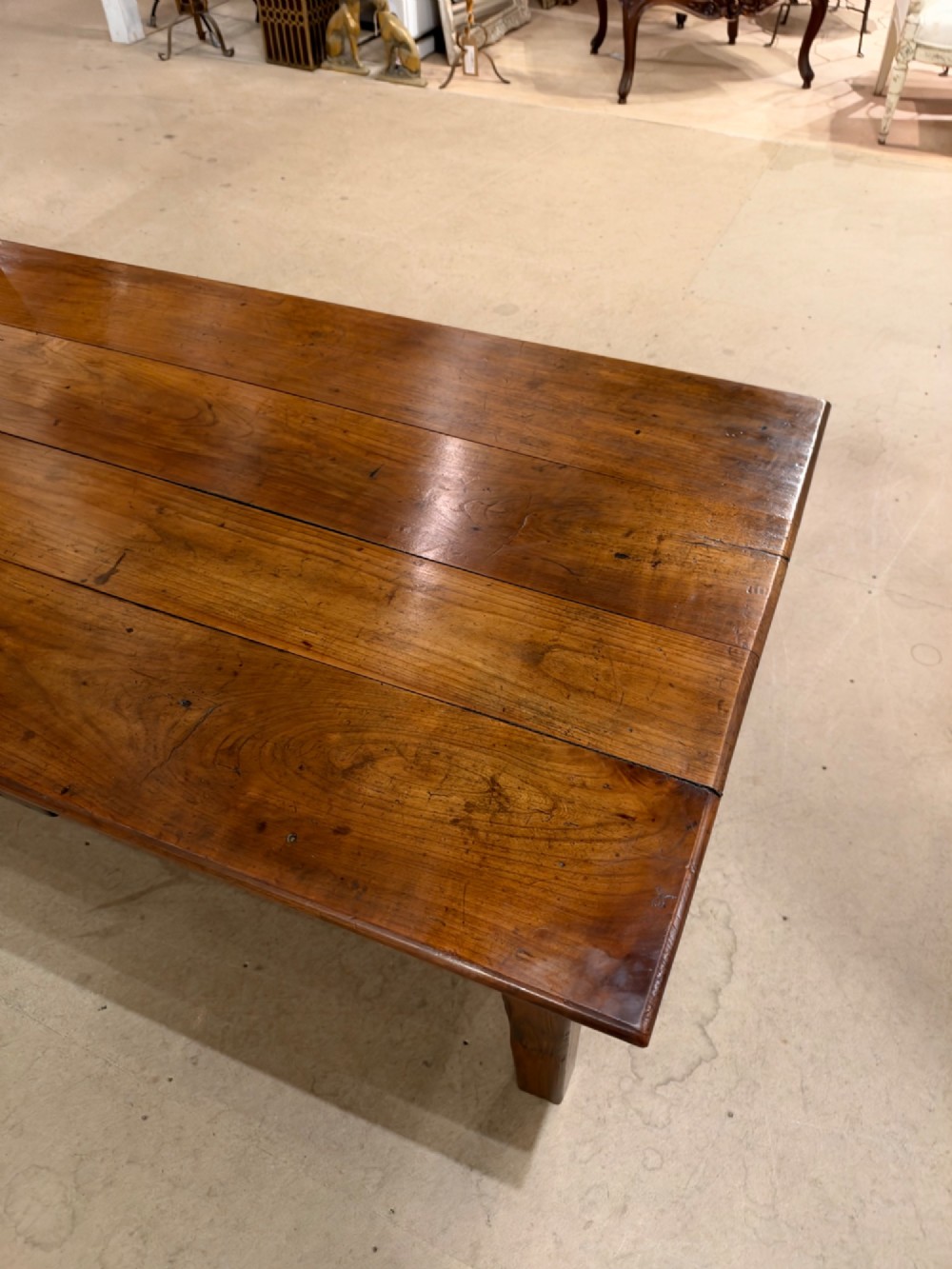 A large rectangular warm brown cherrywood coffee table featuring a plank top, tapered square legs, and a small drawer with a ring pull handle. View IX
