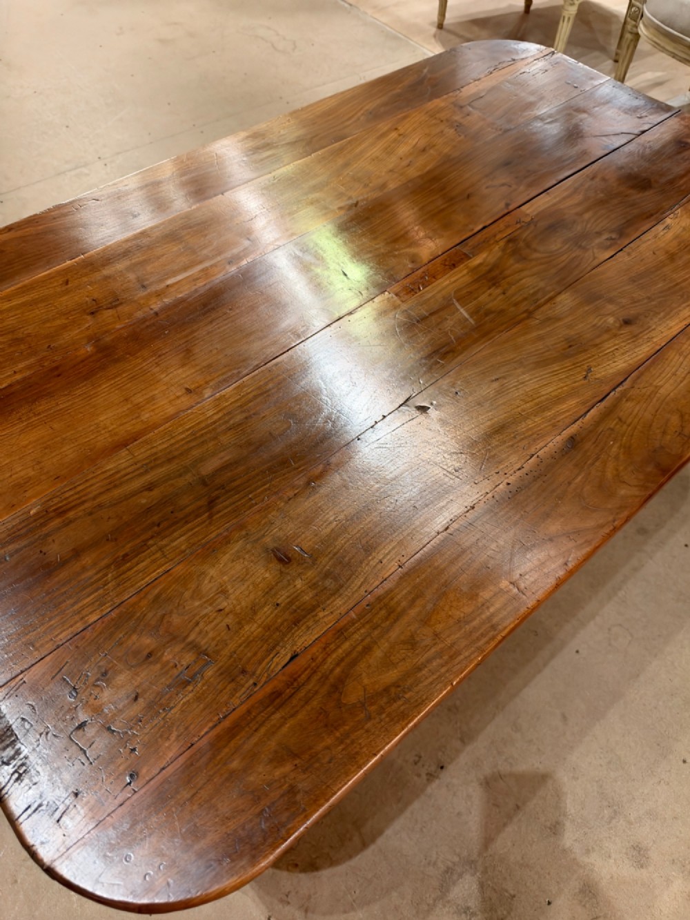 A low rectangular cherrywood coffee table featuring a plank top with rounded corners, tapered square legs, and a small side drawer. View III
