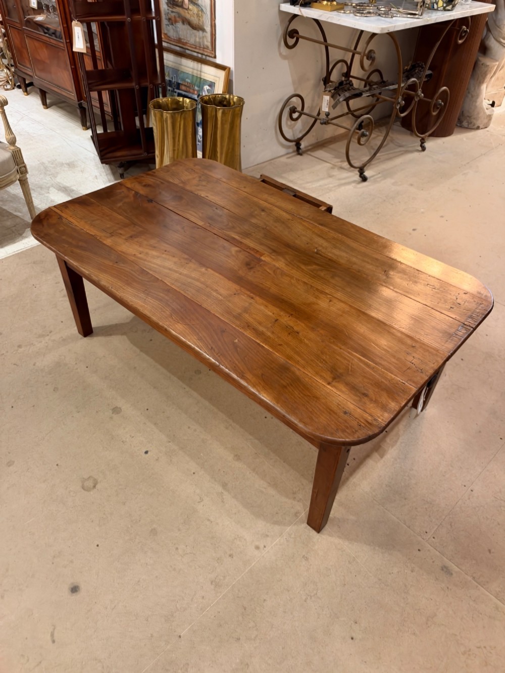 A low rectangular cherrywood coffee table featuring a plank top with rounded corners, tapered square legs, and a small side drawer. View IX