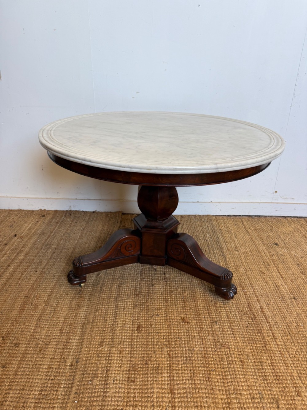 A 19th-century circular centre table featuring a white marble top set on a dark mahogany turned pedestal with a scroll-footed tripod base.