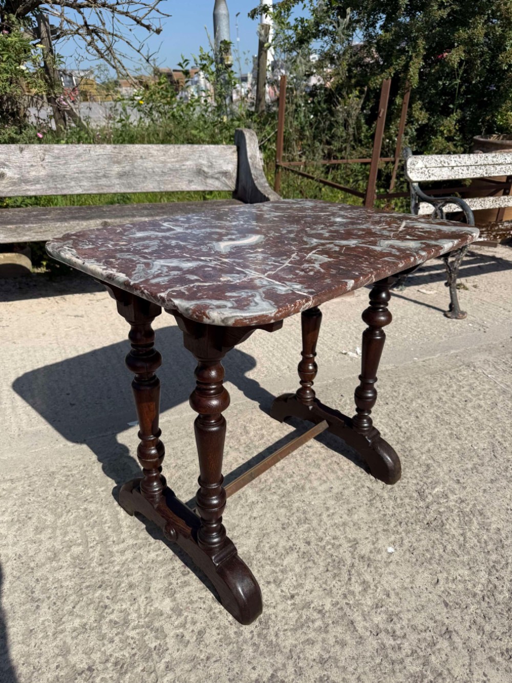 A 19th-century French table a gibier featuring a red and grey veined marble top resting on a dark turned timber base with a low stretcher.