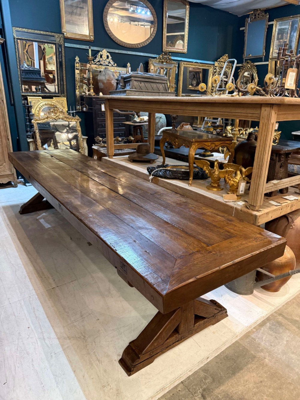A long late 19th-century French oak refectory table featuring a thick plank top with cleated ends resting on sturdy trestle legs and a stretcher base.