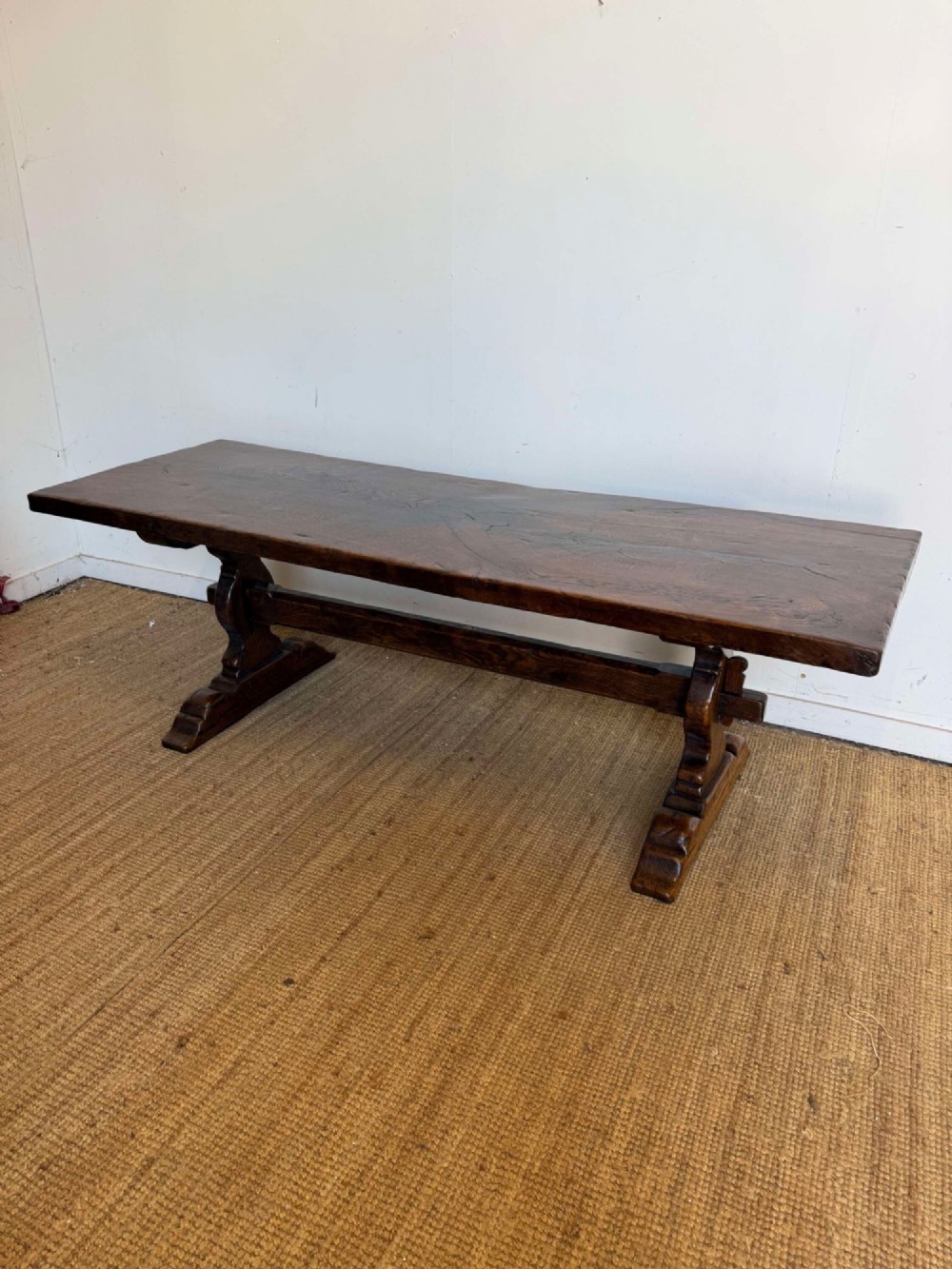 An early 20th century French dark oak refectory table featuring a single plank top supported by a pegged trestle base with a central stretcher.