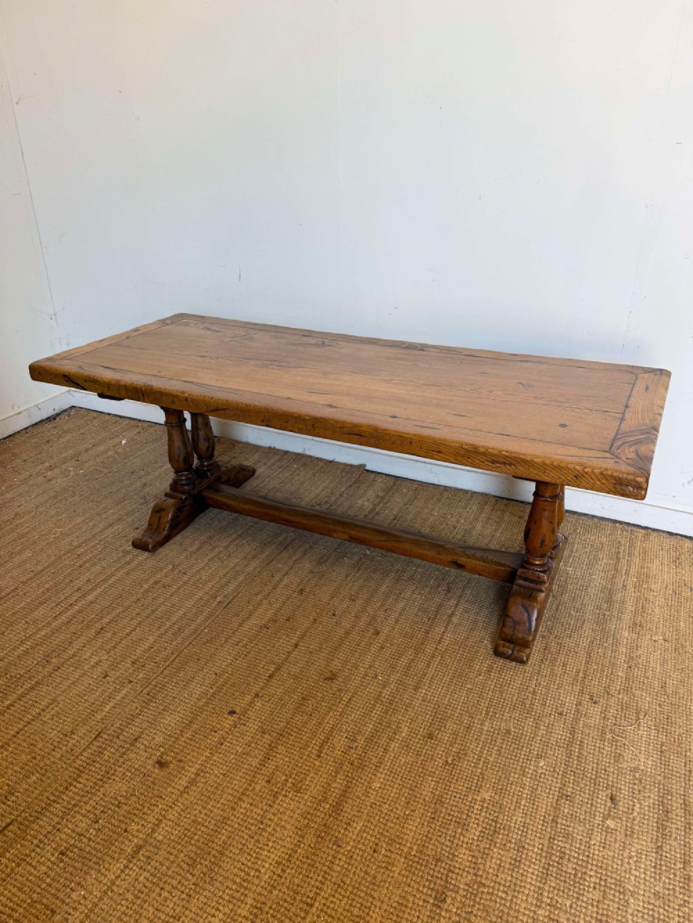 An early 20th-century oak refectory dining table featuring a rectangular framed plank top supported by turned legs on a trestle base with a stretcher rail.