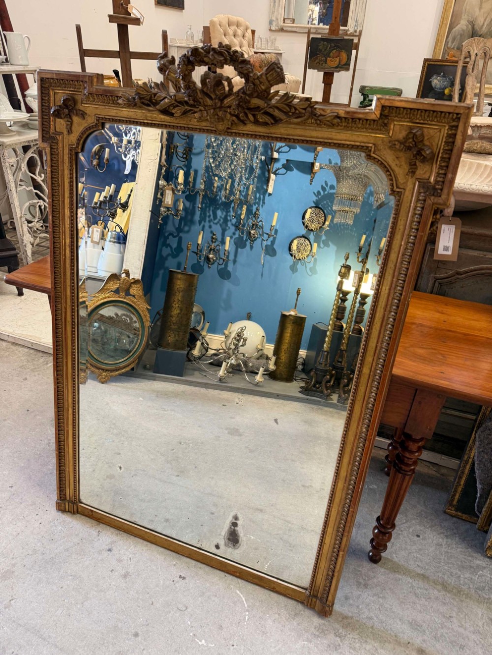 A large 19th-century French Louis Philippe rectangular mirror featuring a gilded frame with rounded top corners, beaded inner moulding, and an ornate floral crest at the top centre.