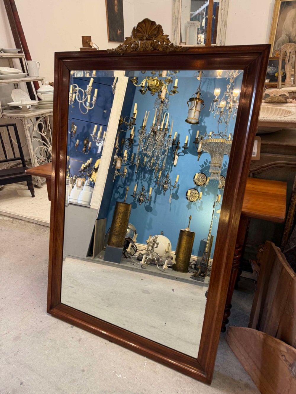A large rectangular mahogany wall mirror featuring a moulded timber frame and a carved ormolu foliate cresting at the top.