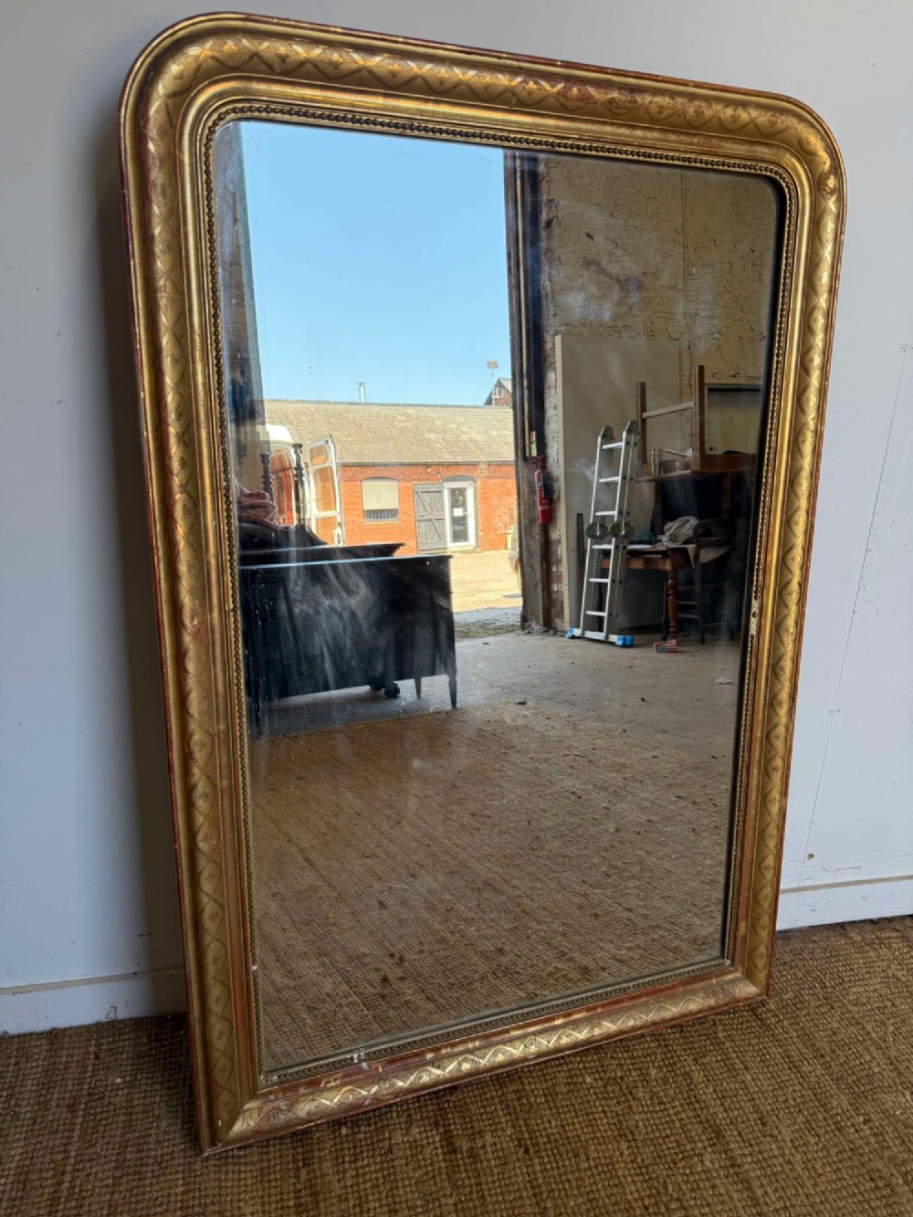 A late nineteenth-century French rectangular wall mirror featuring rounded upper corners, an incised gold gilt frame, and a beaded inner border.