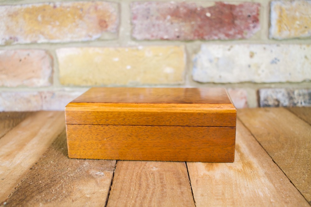 A rectangular polished mahogany trinket box with a hinged lid and smooth wood grain surface.