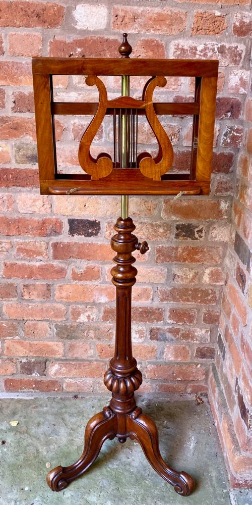 An antique mahogany duet music stand featuring double lyre-shaped rests, an adjustable brass stem, and a turned pedestal base on tripod feet. View VIII