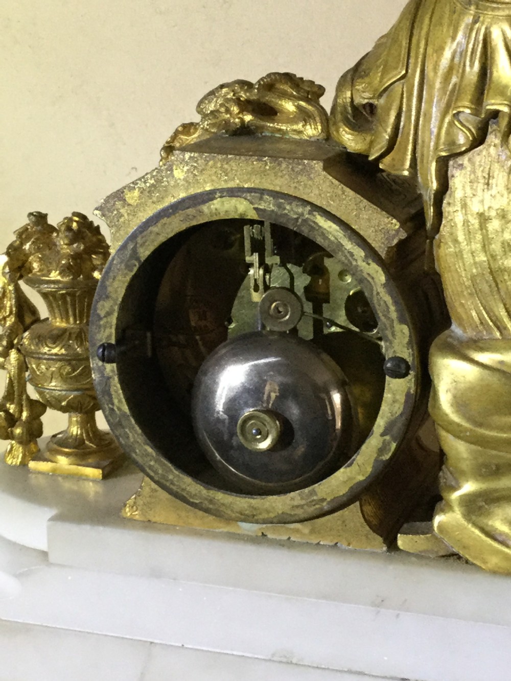 An antique French Empire mantel clock featuring a gilded bronze classical female figure leaning against a white enamel clock face set upon a stepped white marble base. View XII
