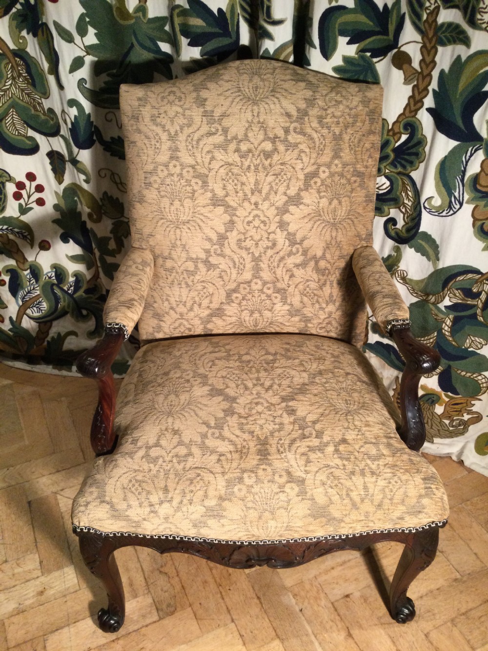 An upholstered open armchair featuring dark mahogany carved cabriole legs and patterned beige fabric upholstery. View II