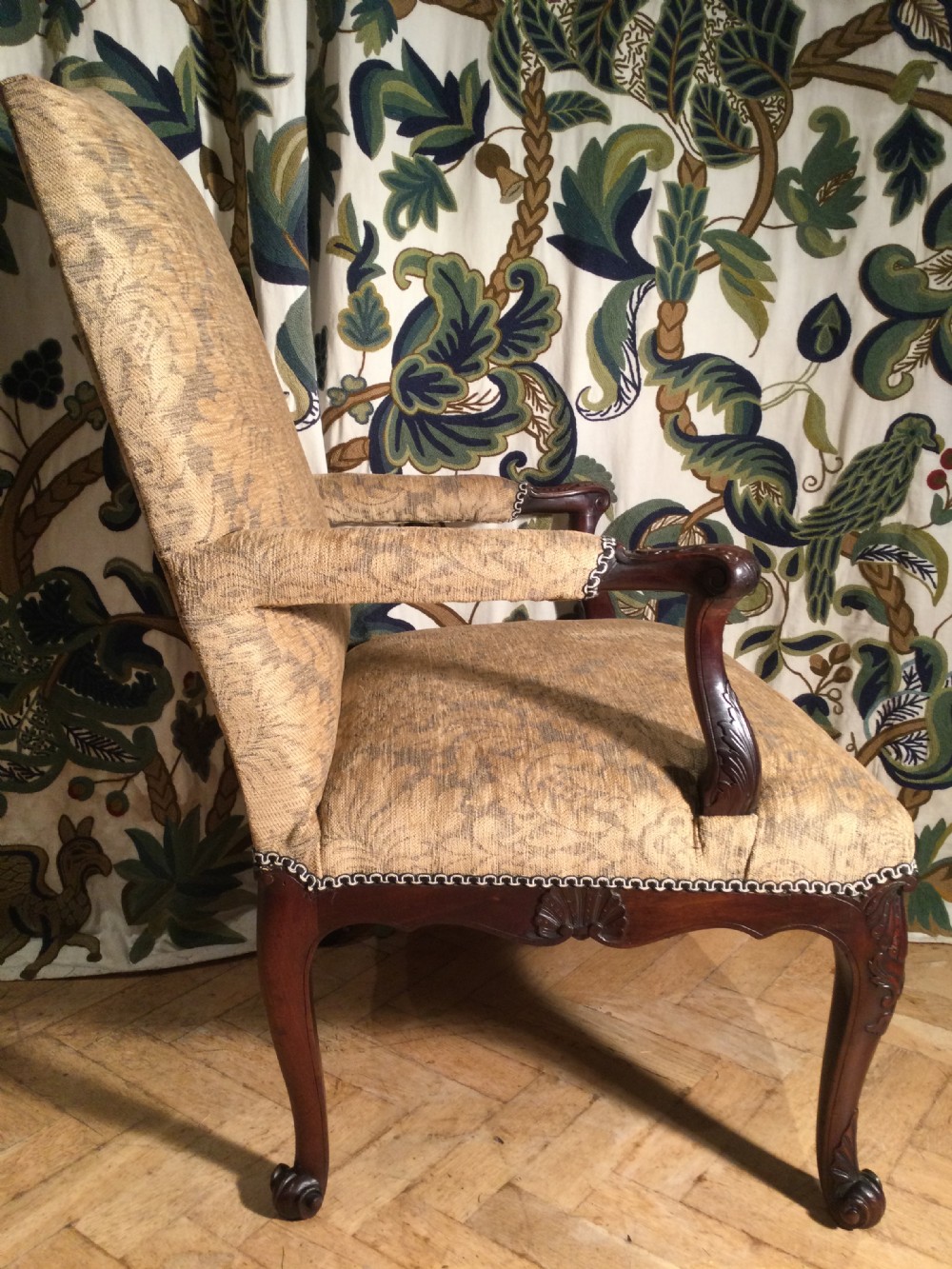 An upholstered open armchair featuring dark mahogany carved cabriole legs and patterned beige fabric upholstery. View IV