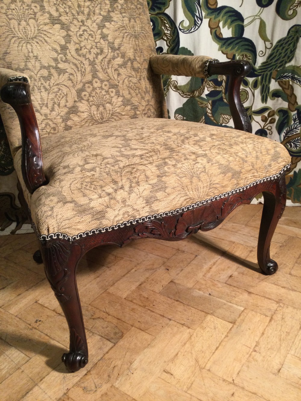 An upholstered open armchair featuring dark mahogany carved cabriole legs and patterned beige fabric upholstery. View V