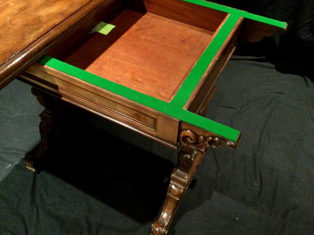 An antique William IV flame mahogany fold-over card table featuring carved scroll brackets, a rectangular top, and a carved trestle base. View VIII