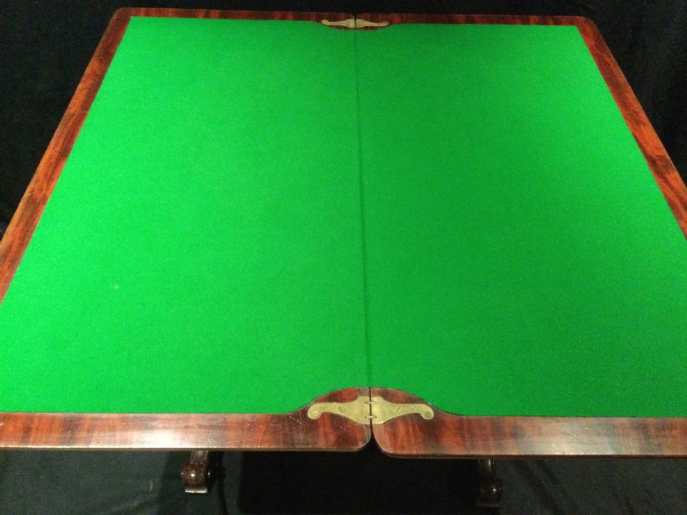 An antique William IV flame mahogany fold-over card table featuring carved scroll brackets, a rectangular top, and a carved trestle base. View IX