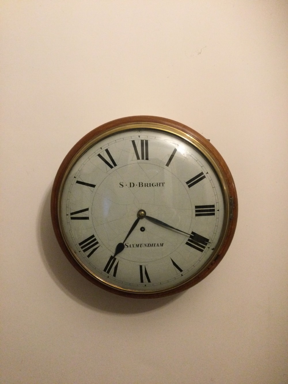 A circular Victorian dial wall clock featuring a warm mahogany bezel, an off-white painted dial with craquelure, black Roman numerals, and steel spade hands. View III