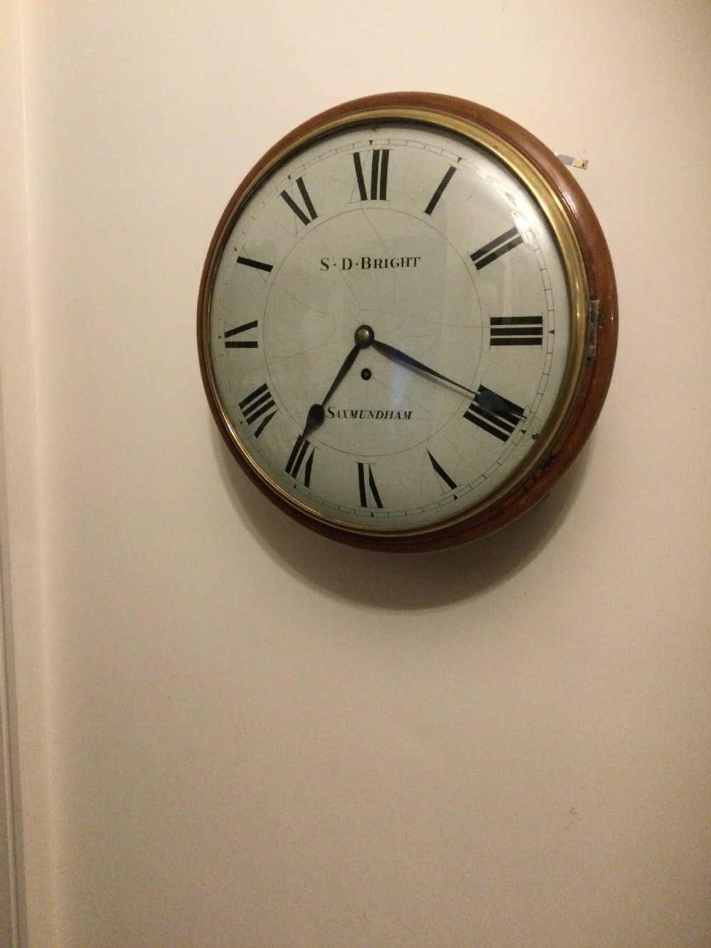 A circular Victorian dial wall clock featuring a warm mahogany bezel, an off-white painted dial with craquelure, black Roman numerals, and steel spade hands. View V
