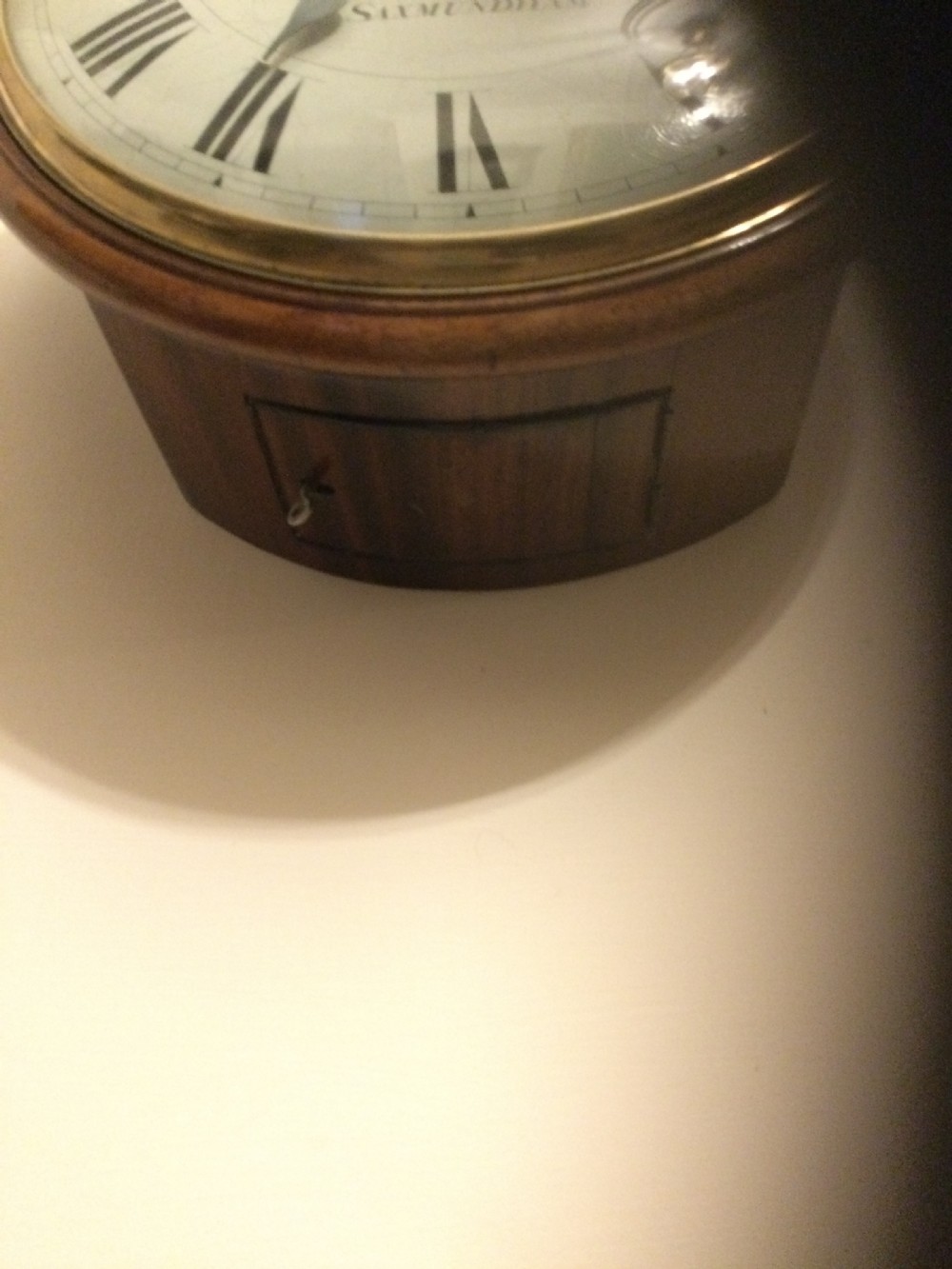 A circular Victorian dial wall clock featuring a warm mahogany bezel, an off-white painted dial with craquelure, black Roman numerals, and steel spade hands. View IX