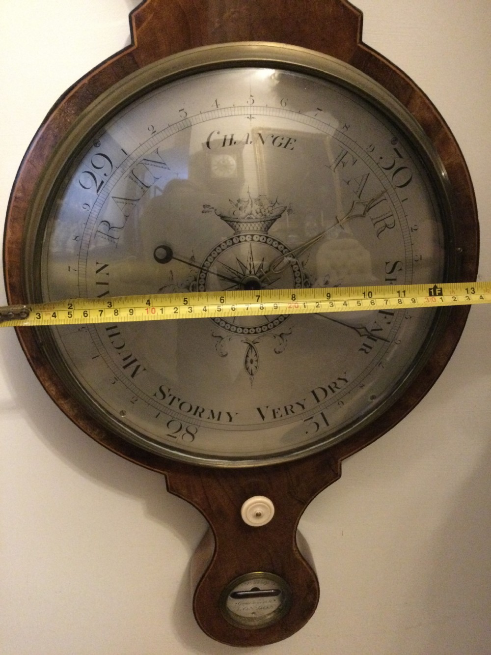 A wall-mounted Georgian mahogany banjo barometer featuring a swan-neck pediment, brass finial, hygrometer dial, central spirit thermometer, and lower dial. View VII