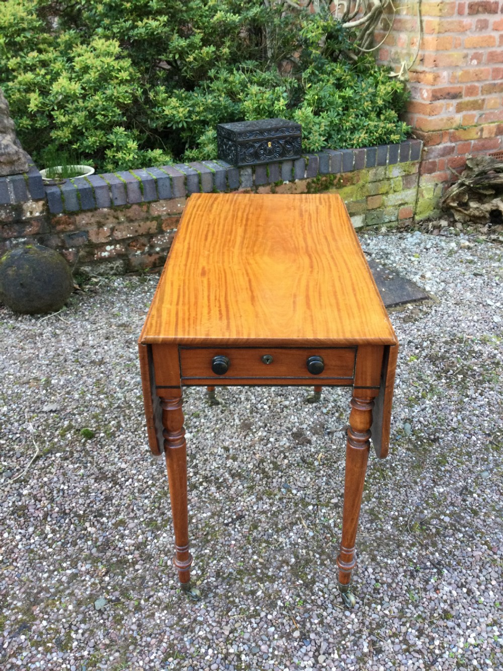 A Regency mahogany Pembroke table featuring two hinged drop leaves, turned legs fitted with brass castors, and a single frieze drawer with turned wooden knobs. View IV