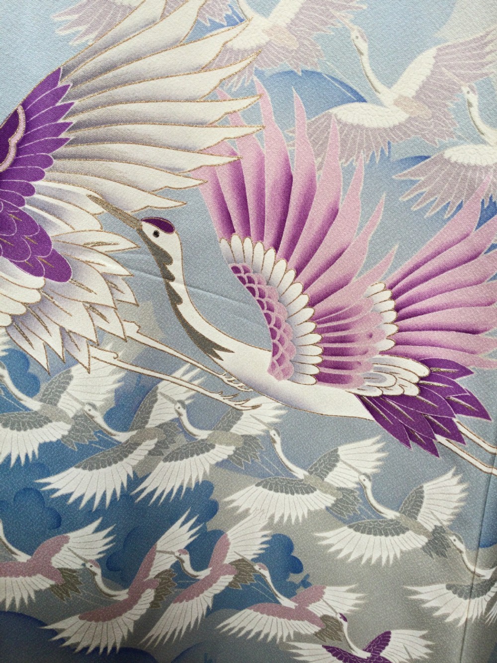 A full-length Japanese silk kimono in light blue decorated with flying purple and white cranes among stylized cloud motifs. View II