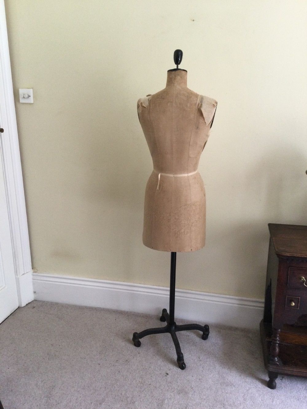 A vintage French Stockman dressmaker mannequin with a beige fabric-covered torso supported by a black cast iron stand. View V