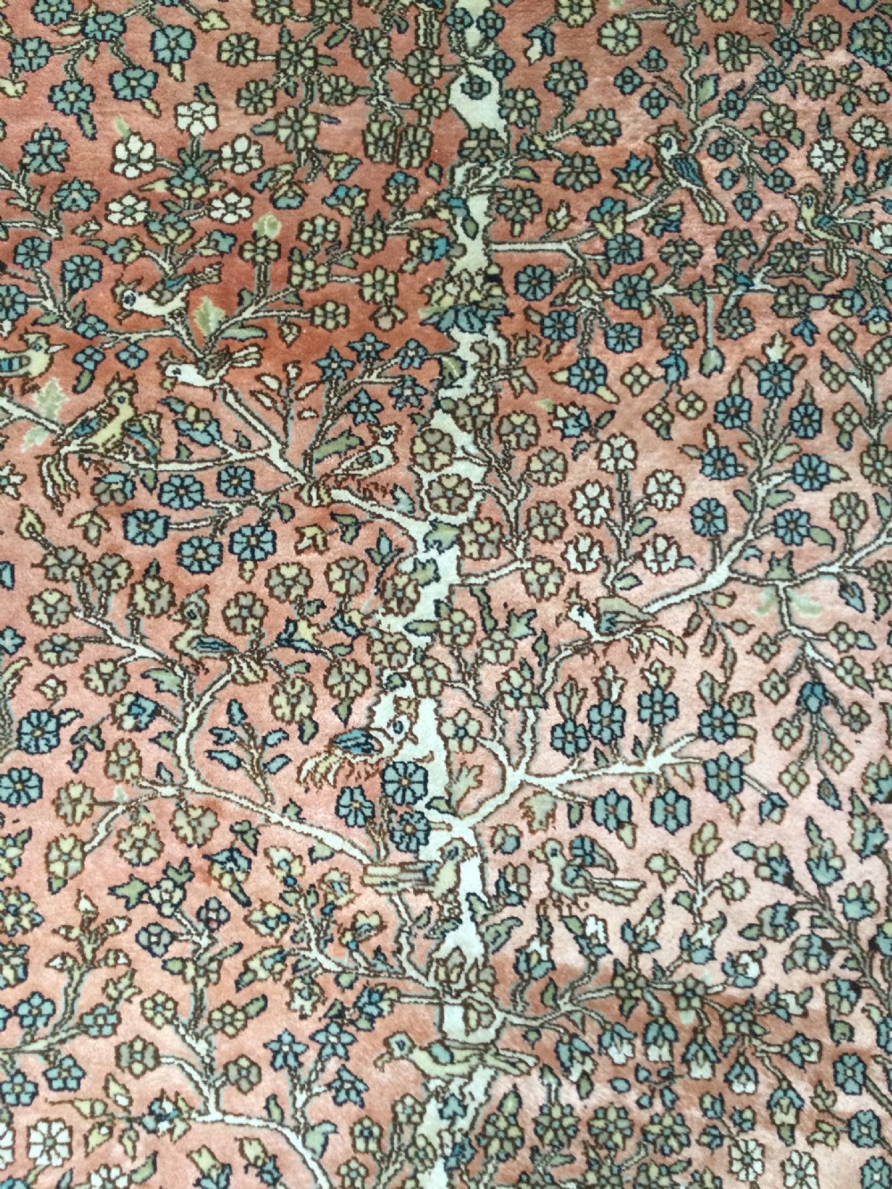 A rectangular hand-knotted Persian rug featuring a central terracotta field filled with a detailed Tree of Life and bird pattern framed by a dark navy floral border. View III