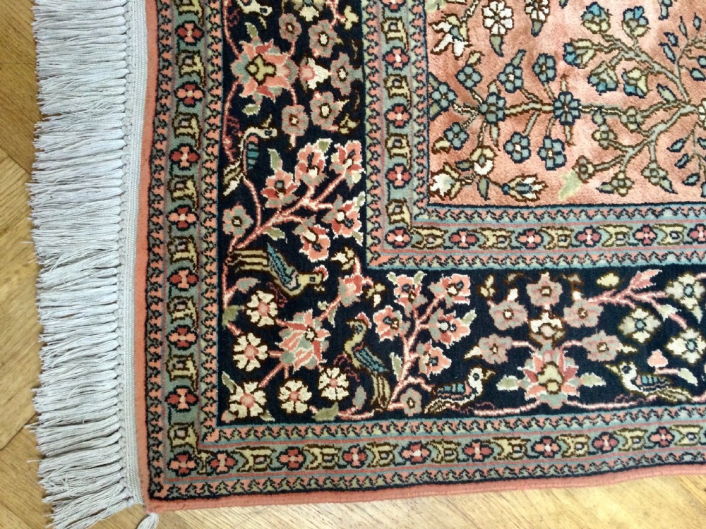 A rectangular hand-knotted Persian rug featuring a central terracotta field filled with a detailed Tree of Life and bird pattern framed by a dark navy floral border. View VI