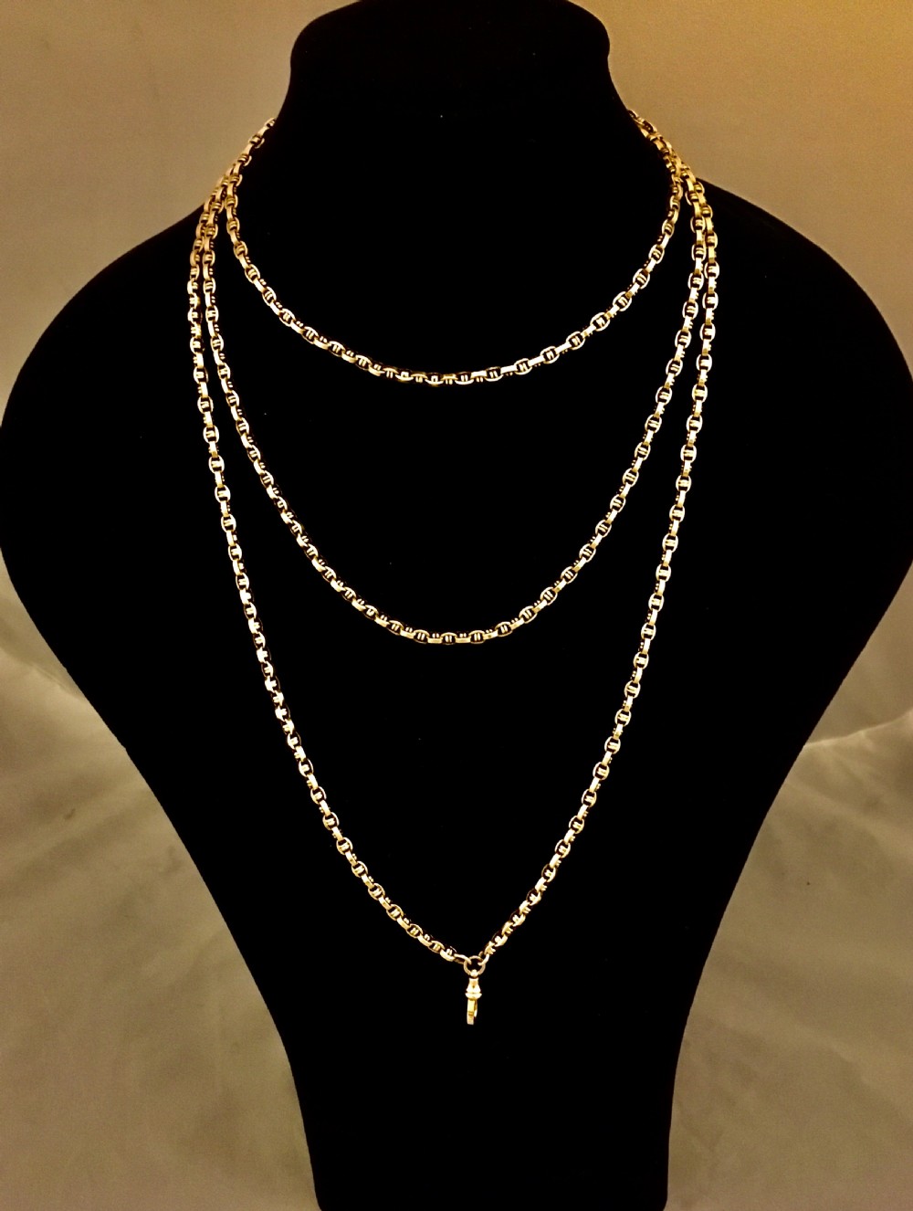 A long yellow gold link chain displayed in multiple loops against a dark background.