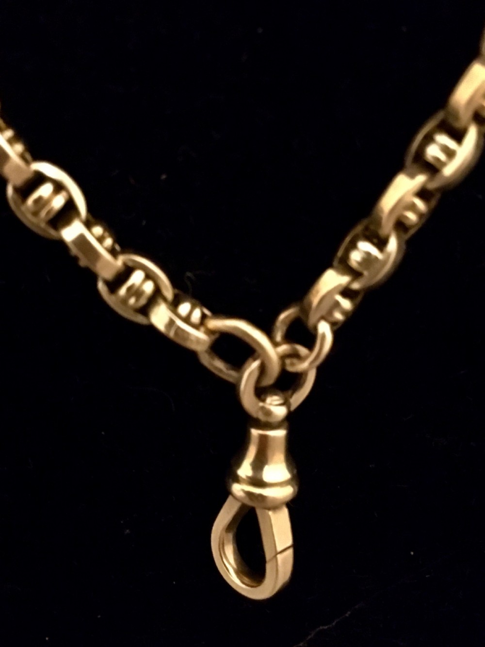 A long yellow gold link chain displayed in multiple loops against a dark background. View IV