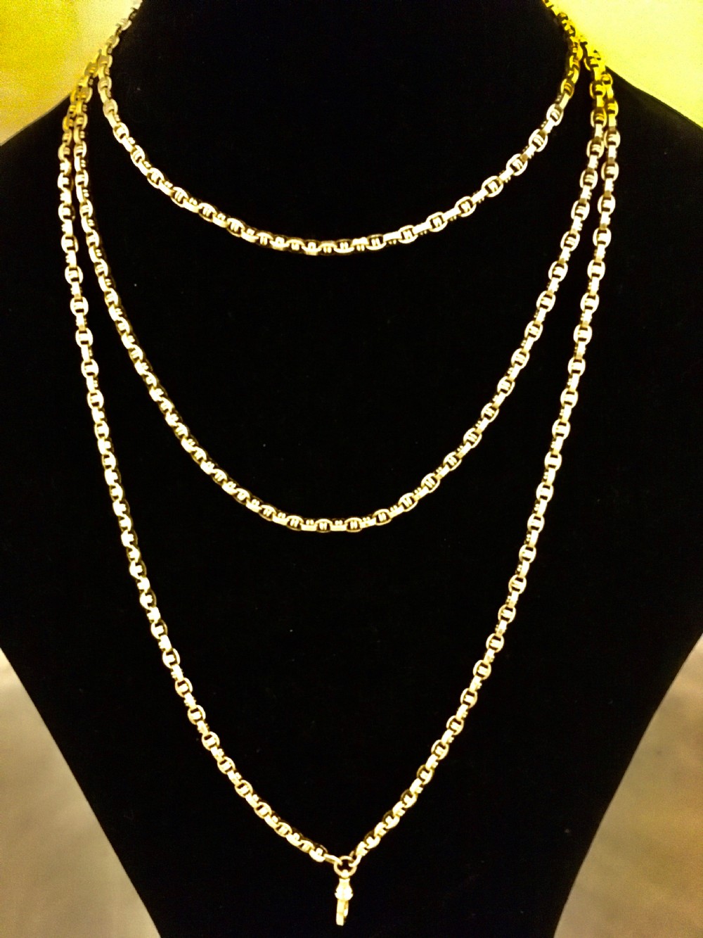 A long yellow gold link chain displayed in multiple loops against a dark background. View VI