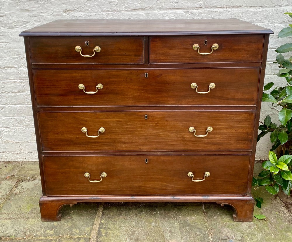 A Georgian mahogany chest of drawers featuring two short drawers over three long drawers with brass swan-neck handles and shaped bracket feet.